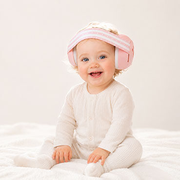 bébé souriant, assis sur une couverture blanche